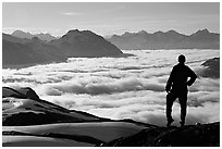 Hiker contemplaing a sea of clouds. Kenai Fjords National Park, Alaska, USA. (black and white)