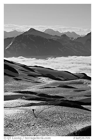 Mountains and sea of clouds, hiker on snow-covered trail. Kenai Fjords National Park, Alaska, USA.