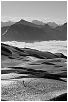 Mountains and sea of clouds, hiker on snow-covered trail. Kenai Fjords National Park ( black and white)