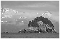 Rocky islet and snowy peaks, Aialik Bay. Kenai Fjords National Park, Alaska, USA. (black and white)