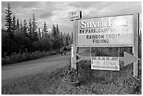Sign and couple walking on McCarthy road near Silver Lake. Wrangell-St Elias National Park ( black and white)