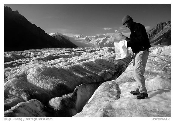 Hiker checks map on Root Glacier. Wrangell-St Elias National Park, Alaska, USA.