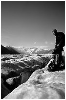 Hiker reaches for item in backpack on Root Glacier. Wrangell-St Elias National Park, Alaska, USA. (black and white)