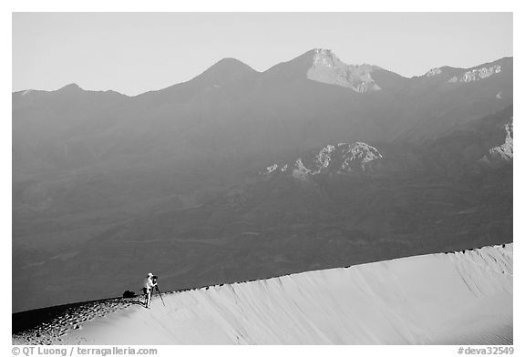 Photographer on dune ridge at sunrise. Death Valley National Park, California, USA.