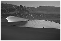 Hiker on ridge, Mesquite Dunes, sunrise. Death Valley National Park, California, USA. (black and white)