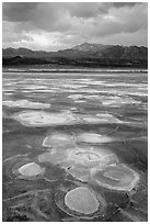 Salt evaporation patterns and Funeral Mountains at sunset, Cottonball Basin. Death Valley National Park ( black and white)