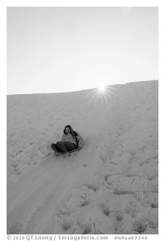 Woman sledding down dune. White Sands National Park (black and white)