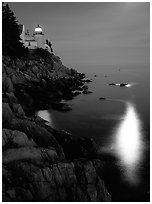 Bass Harbor lighthouse by night with reflections of moon and lighthouse light. Acadia National Park, Maine, USA. (black and white)