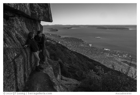 Hikers resting on ledge with handrails. Acadia National Park (black and white)
