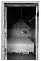 Bed framed by door of single-room Honeymoon cabin, Edisen Fishery. Isle Royale National Park ( black and white)