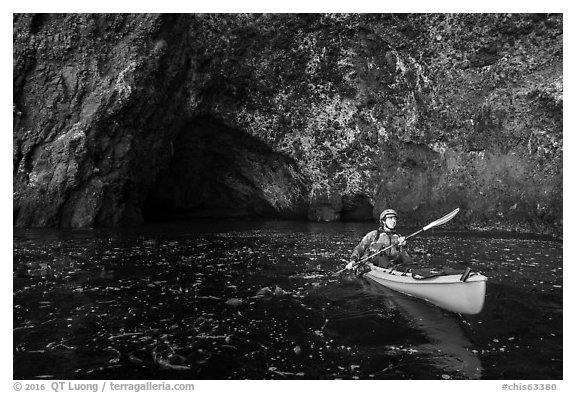 Kayaker paddling out of sea cave, Santa Cruz Island. Channel Islands National Park (black and white)