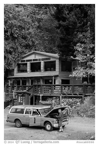 Man fixing old car in front of North Cascades Lodge, Stehekin, North Cascades National Park Service Complex.  (black and white)