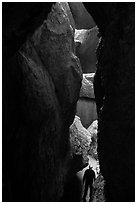 Hiker in narrow and deep section of Lower Bear Gulch Cave. Pinnacles National Park ( black and white)