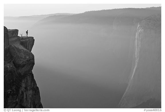 Hiker standing on top of sheer cliff at Taft point. Yosemite National Park (black and white)