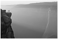 Hiker standing on top of sheer cliff at Taft point. Yosemite National Park ( black and white)