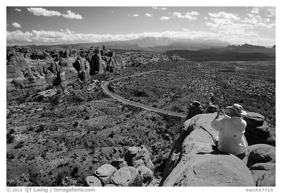 Tourist taking picture from top of fin. Arches National Park (black and white)