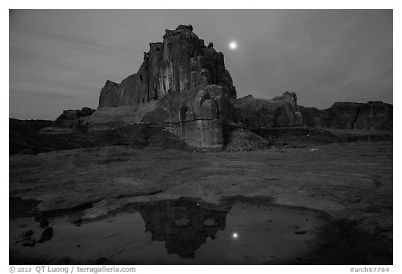 Courthouse tower and moon reflected in pothole. Arches National Park, Utah, USA.