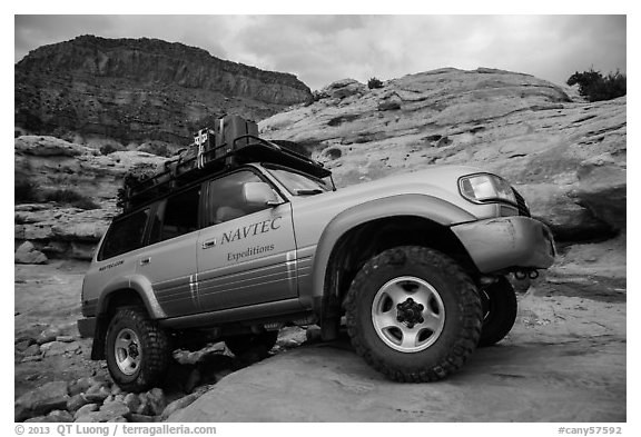Expedition vehicle driving over rock ledge, Teapot Canyon. Canyonlands National Park (black and white)