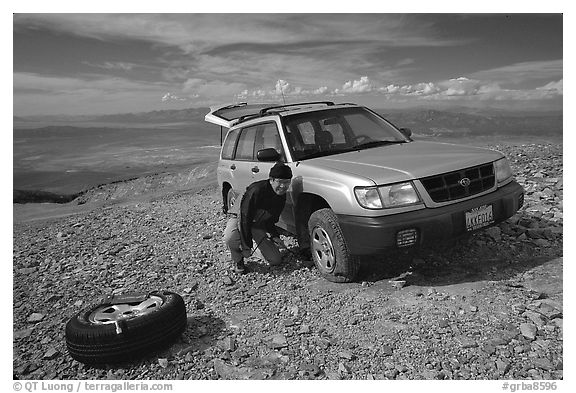 Man changing a flat tire on remote spot at top of Mt Washington. Great Basin National Park (black and white)