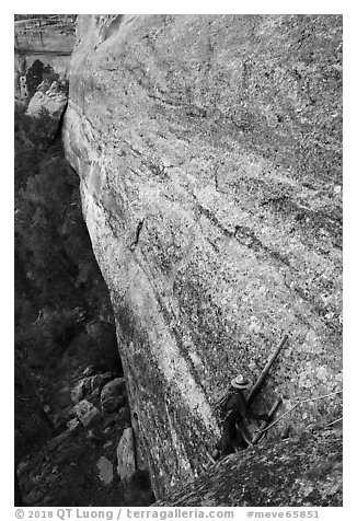 Park ranger on ladder along steep cliff leading to ruin. Mesa Verde National Park (black and white)