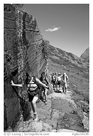 Walking under a small waterfall on the Grinnell Glacier trail. Glacier National Park (black and white)