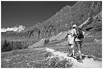 Hikers on trail amongst wildflowers near Hidden Lake. Glacier National Park ( black and white)