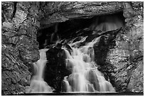 Water flows of opening in cliff face, Running Eagle Falls. Glacier National Park ( black and white)