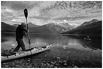 Kayaker steps into kayak, Kintla Lake. Glacier National Park ( black and white)