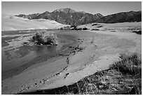 Banks of flowing Medano Creek, dunes and mountains. Great Sand Dunes National Park and Preserve ( black and white)