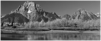 Rugged mountains rising above tree-lined lake in autumn. Grand Teton National Park (Panoramic black and white)