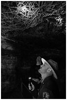 Ranger pointing flashlight at boxwork. Wind Cave National Park ( black and white)