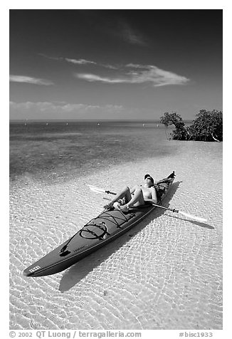 Woman sunning herself on sea kayak parked on shore,  Elliott Key. Biscayne National Park (black and white)