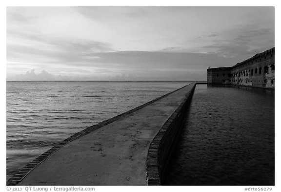 Fort Jefferson moat and walls at sunset with tourists in distance. Dry Tortugas National Park (black and white)