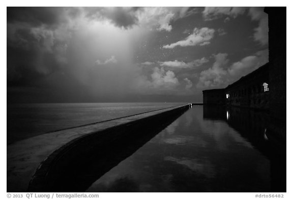 Fort Jefferson seawall at night with sky lit by tropical storm. Dry Tortugas National Park (black and white)