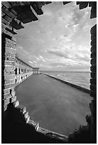 Fort Jefferson seawall and moat, framed by a crumpling embrasures, late afternoon. Dry Tortugas National Park, Florida, USA. (black and white)