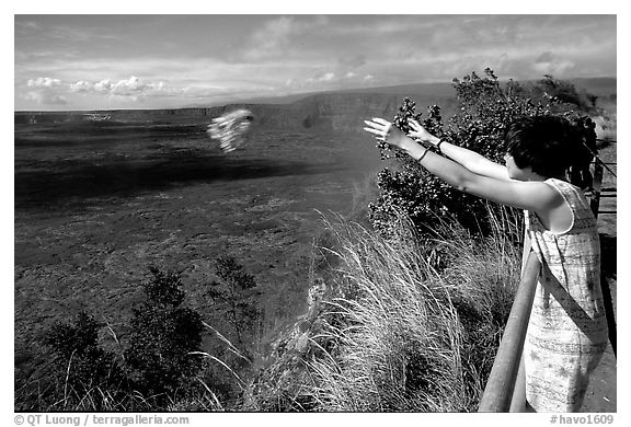 Woman throws flowers into Kilauea caldera as offering to Pele. Hawaii Volcanoes National Park (black and white)