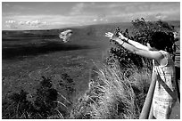 Woman throws flowers into Kilauea caldera as offering to Pele. Hawaii Volcanoes National Park, Hawaii, USA. (black and white)