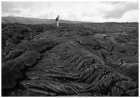 Hiker on hardened lava flow at the end of Chain of Craters road. Hawaii Volcanoes National Park, Hawaii, USA. (black and white)