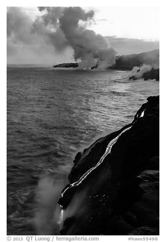 Bright molten lava flows into the Pacific Ocean, plume in background. Hawaii Volcanoes National Park (black and white)