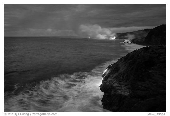 Streams of hot lava flow into the Pacific Ocean at the shore of erupting Kilauea volcano. Hawaii Volcanoes National Park (black and white)