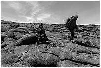 Hiker descending from Mauna Loa summit next to sign. Hawaii Volcanoes National Park, Hawaii, USA. (black and white)