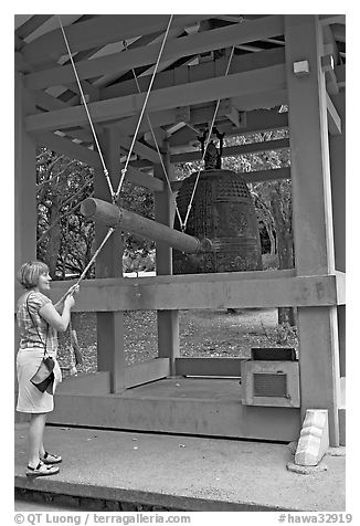Tourist rings the sacred bell before entering Byodo-In temple. Oahu island, Hawaii, USA (black and white)