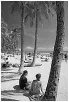 Couple under palm trees on Waikiki beach. Waikiki, Honolulu, Oahu island, Hawaii, USA (black and white)