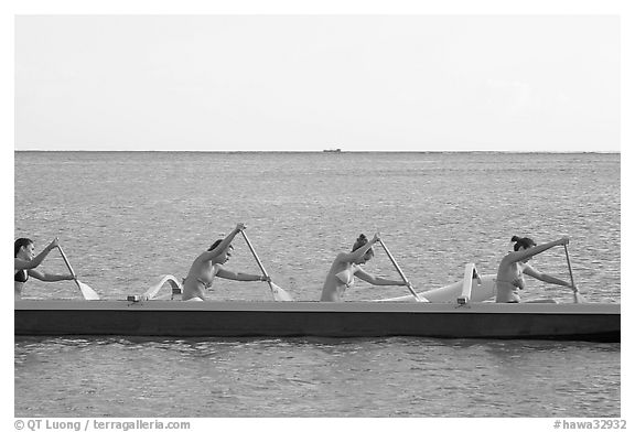 Side view of women in bikini paddling a outrigger canoe, Maunalua Bay, late afternoon. Oahu island, Hawaii, USA (black and white)