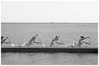 Side view of women in bikini paddling a outrigger canoe, Maunalua Bay, late afternoon. Oahu island, Hawaii, USA ( black and white)
