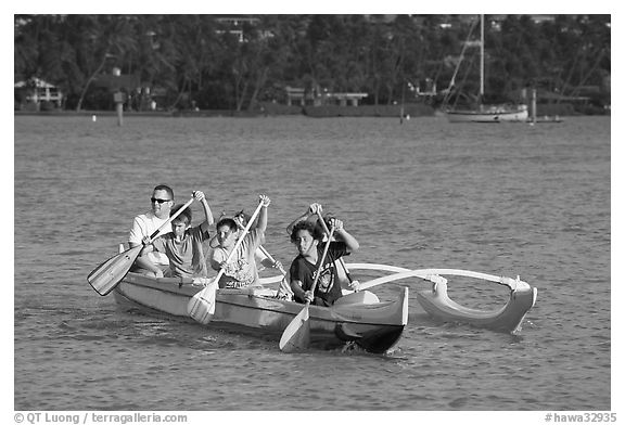 Boys paddling an outrigger canoe, Maunalua Bay, late afternoon. Oahu island, Hawaii, USA (black and white)