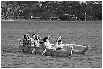 Girls paddling an outrigger canoe, Maunalua Bay, late afternoon. Oahu island, Hawaii, USA (black and white)