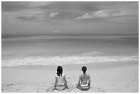 Young women facing the Ocean in a meditative pose on Waimanalo Beach. Oahu island, Hawaii, USA (black and white)