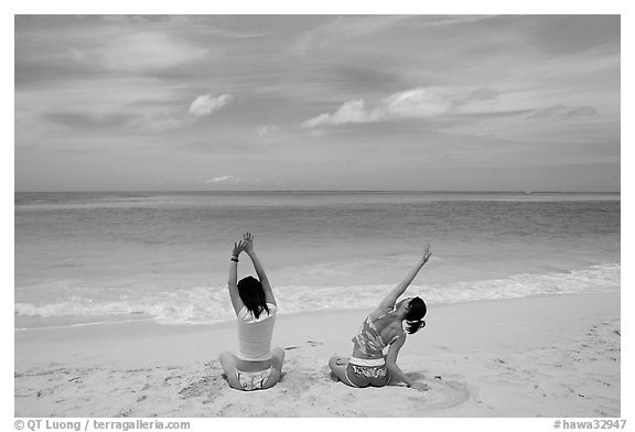 Young women stretching on Waimanalo Beach. Oahu island, Hawaii, USA (black and white)