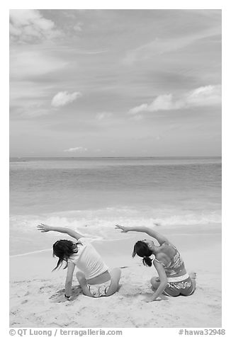 Young women doing gymnastics on Waimanalo Beach. Oahu island, Hawaii, USA (black and white)